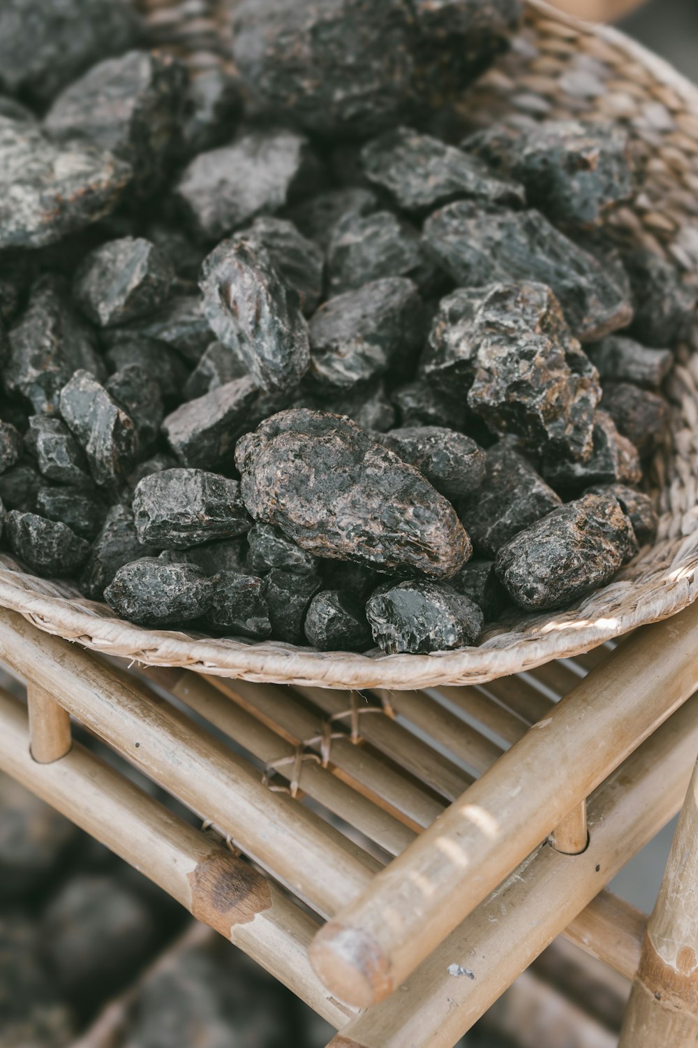 a basket filled with black rocks sitting on top of a wooden chair
