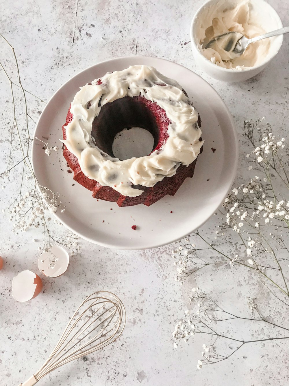 a red velvet cake with cream frosting on a white plate