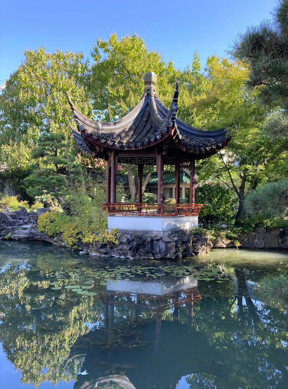 a gazebo in the middle of a pond surrounded by trees