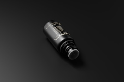 A sleek black bottle is positioned against a dark background. The bottle has elegant gold text on its surface, reflecting a minimalist and luxurious design.