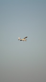 Airplane taking off against a clear blue sky with minimal clouds.
