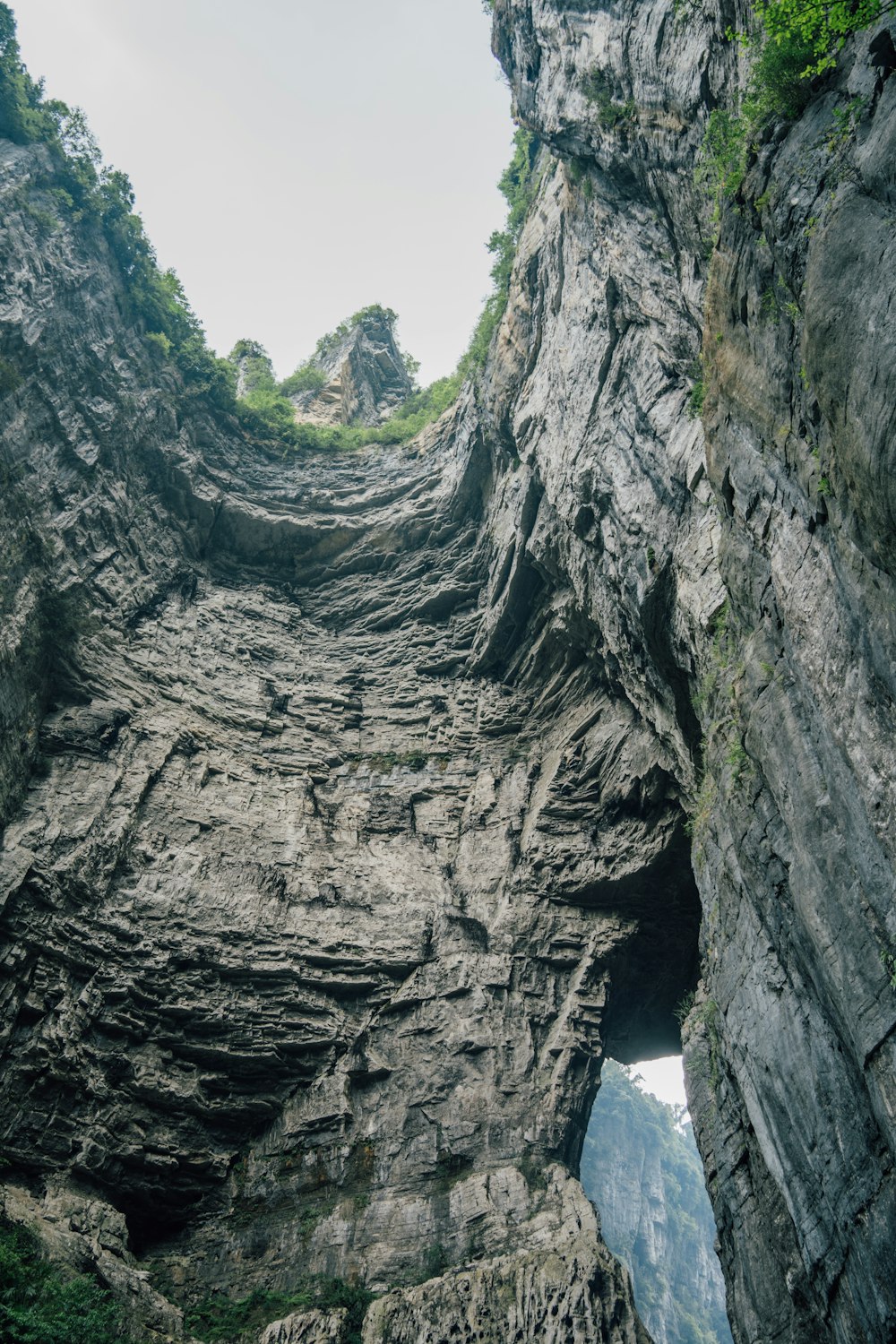a very tall rocky cliff with a small hole in the middle of it