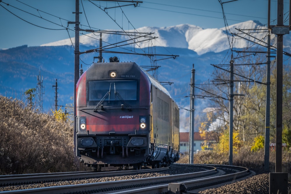 a train traveling down train tracks next to a mountain