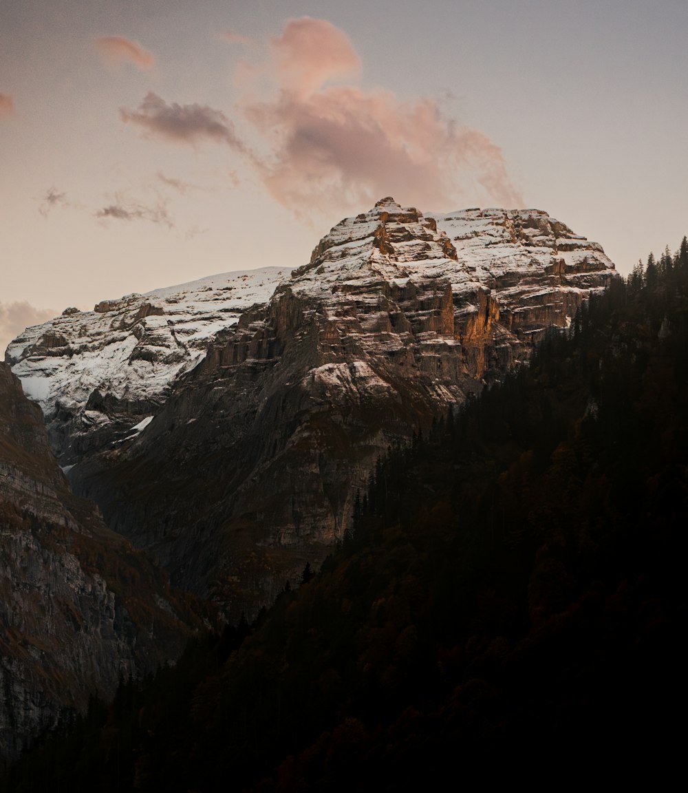 una montagna innevata con alberi e nuvole