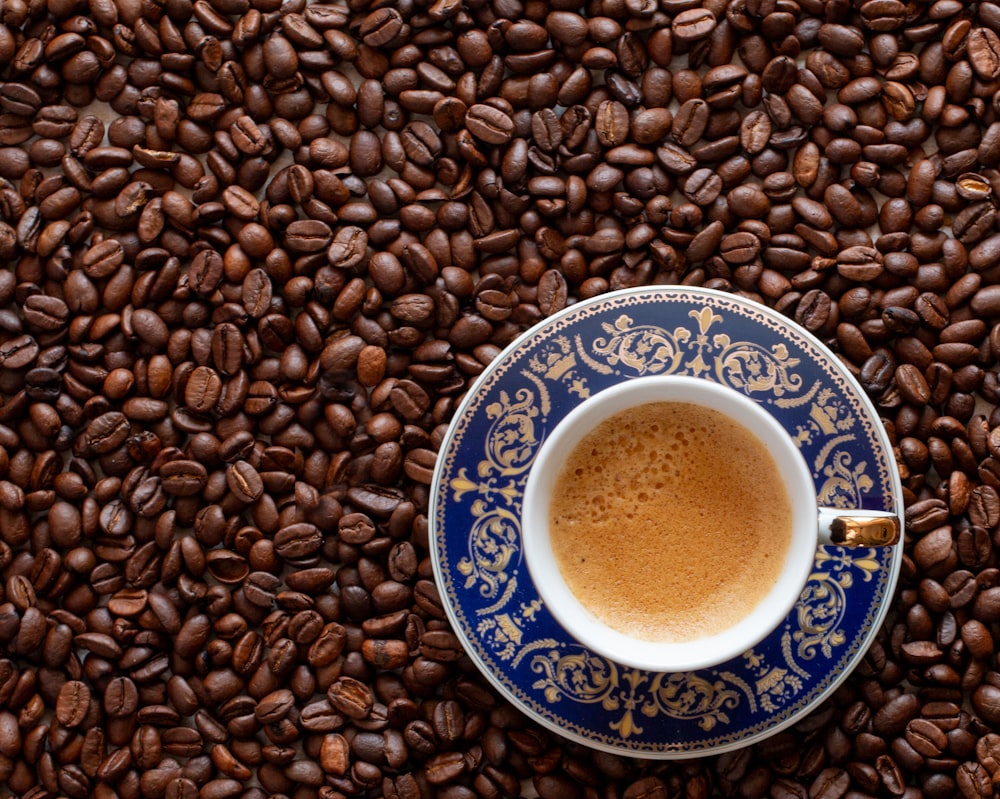 a cup of coffee sitting on top of a pile of coffee beans