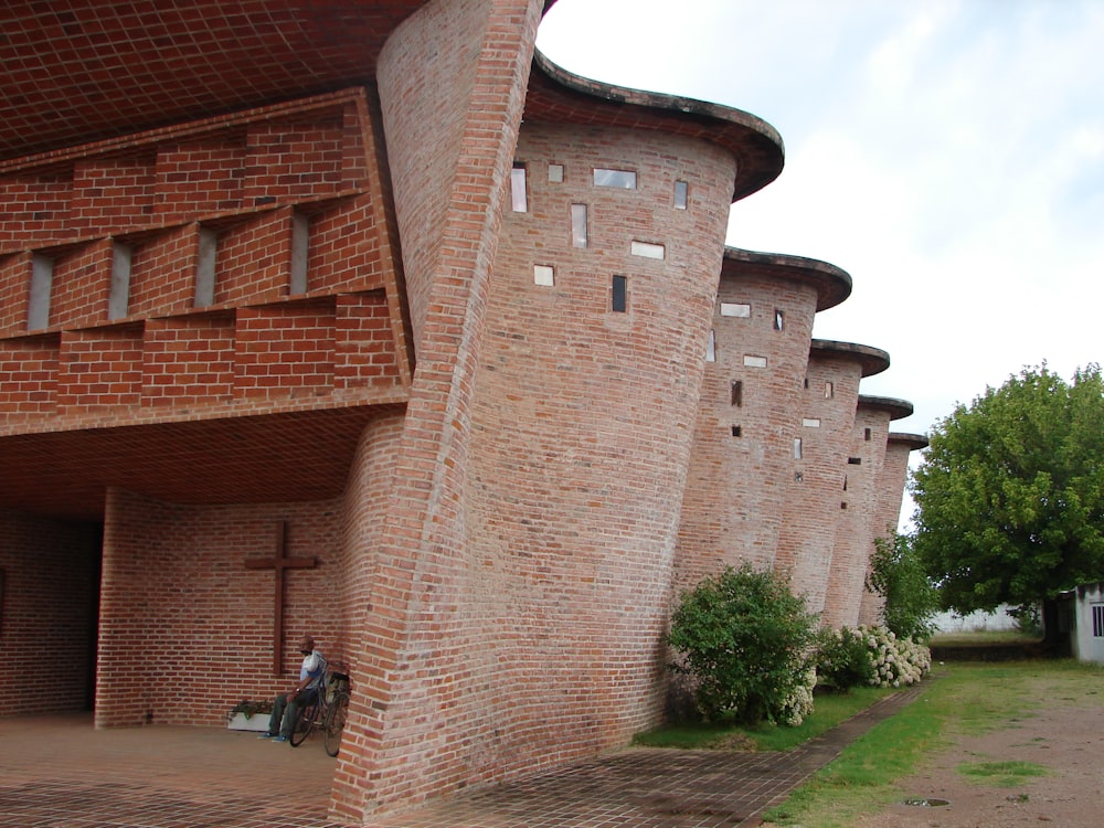 a person sitting on a bench in front of a brick building