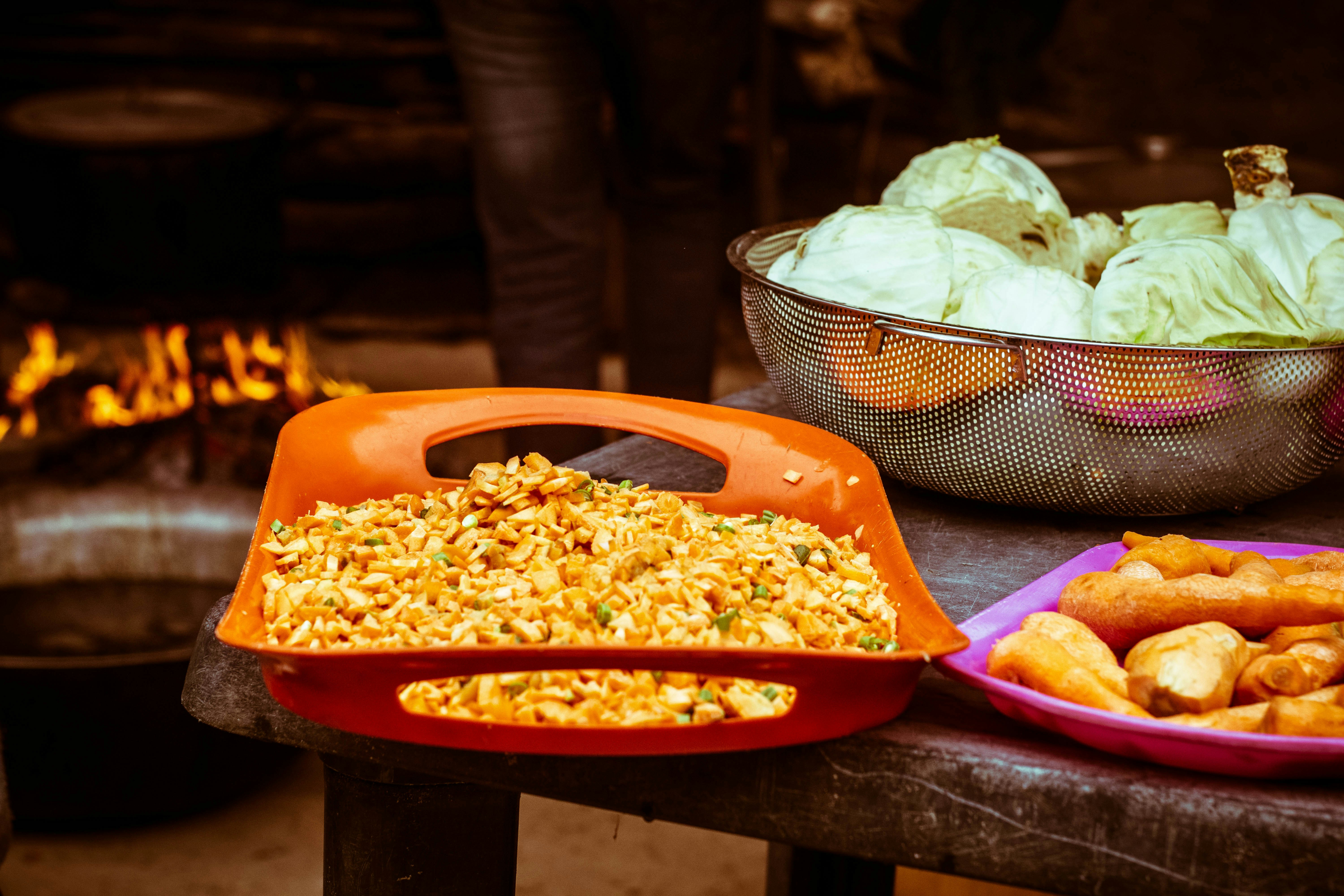 a table topped with bowls of food next to a fire