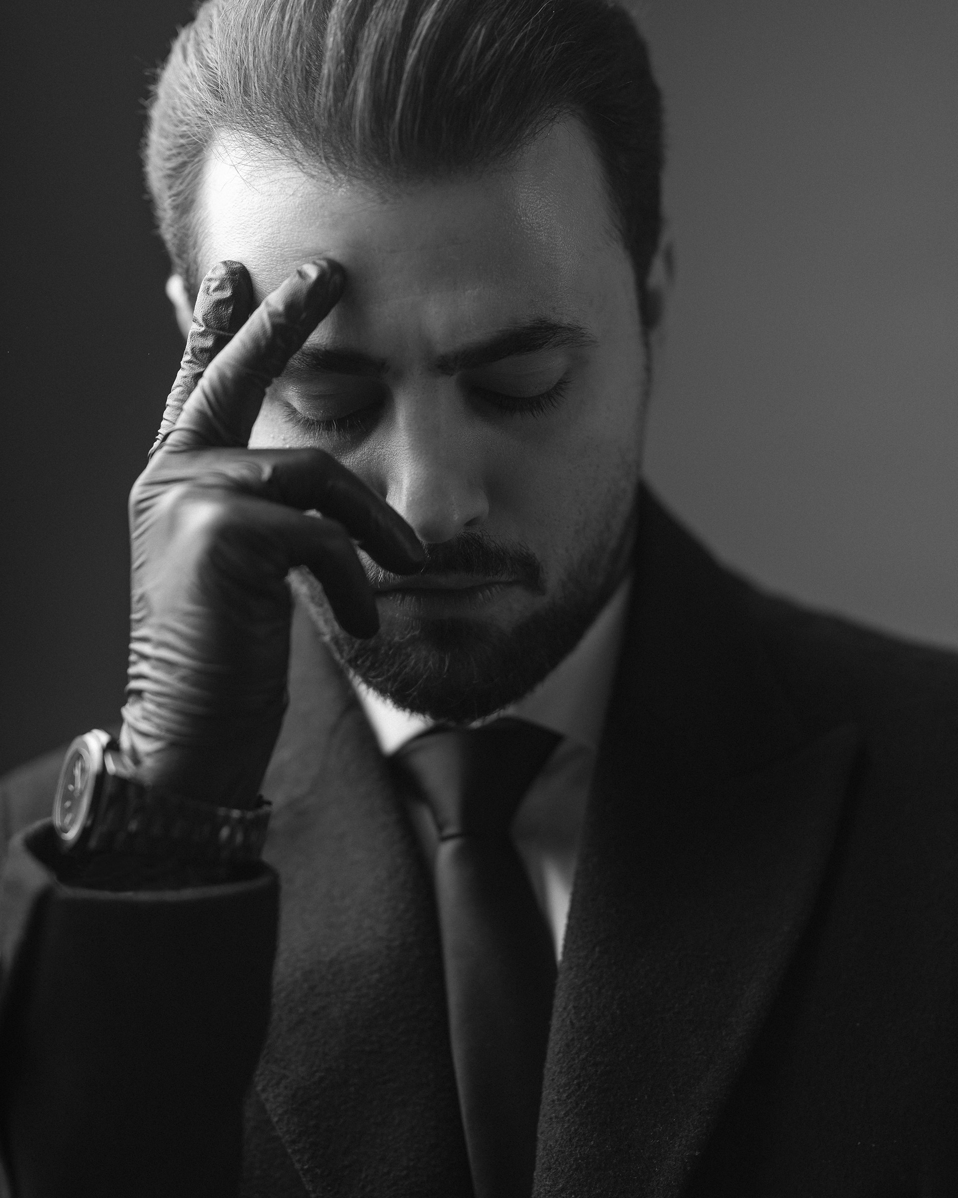 a man in a suit and tie holding his hand to his face