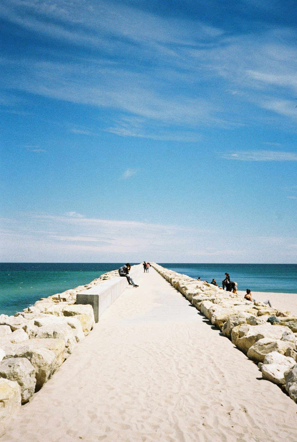 people are sitting on the edge of a long pier