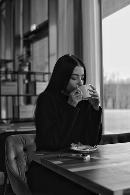 a woman sitting at a table eating a sandwich