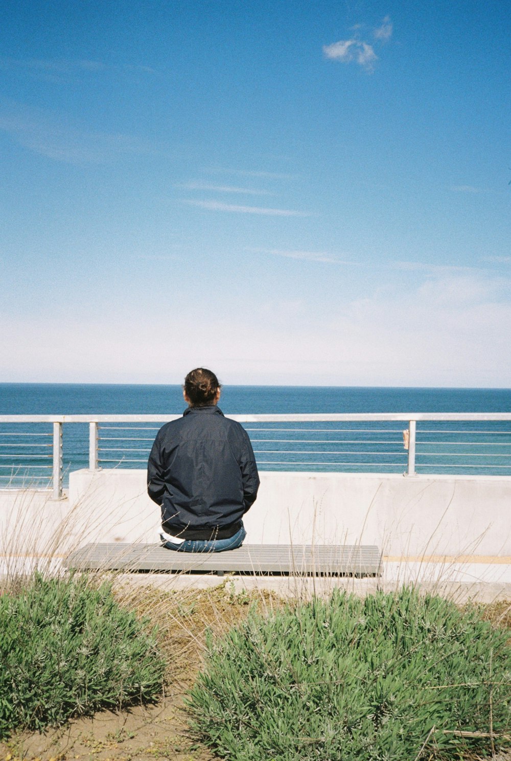 a man sitting on a bench looking out at the ocean