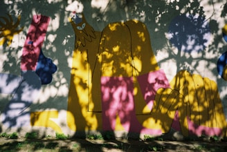 An artist painting a vibrant mural outdoors, sunlight casting dynamic shadows across the colorful scene.