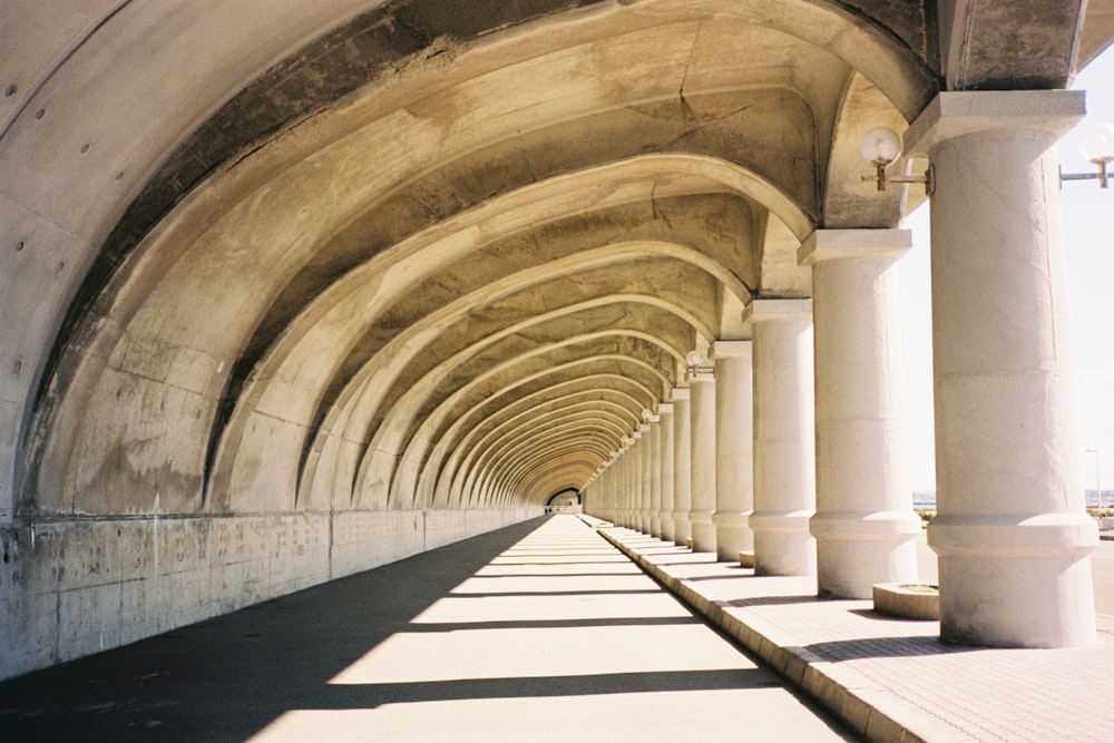 a walkway lined with white pillars and arches