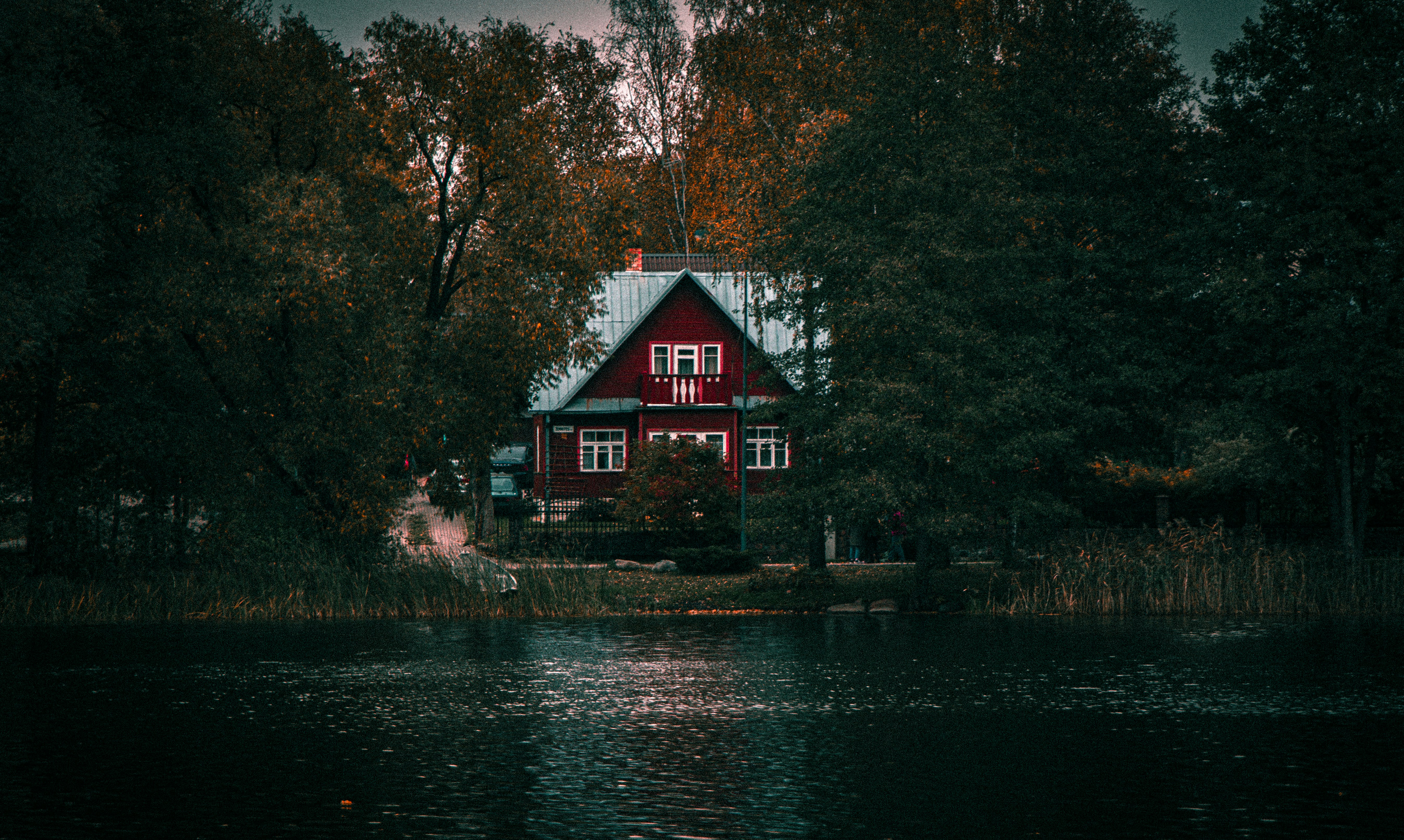 a red house sitting on top of a lake surrounded by trees