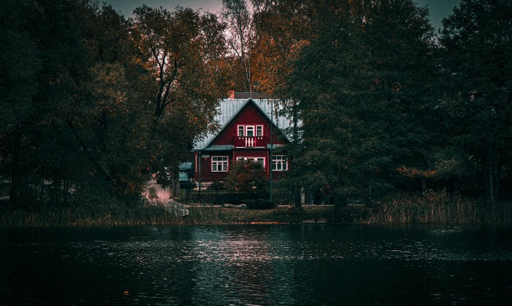 a red house sitting on top of a lake surrounded by trees