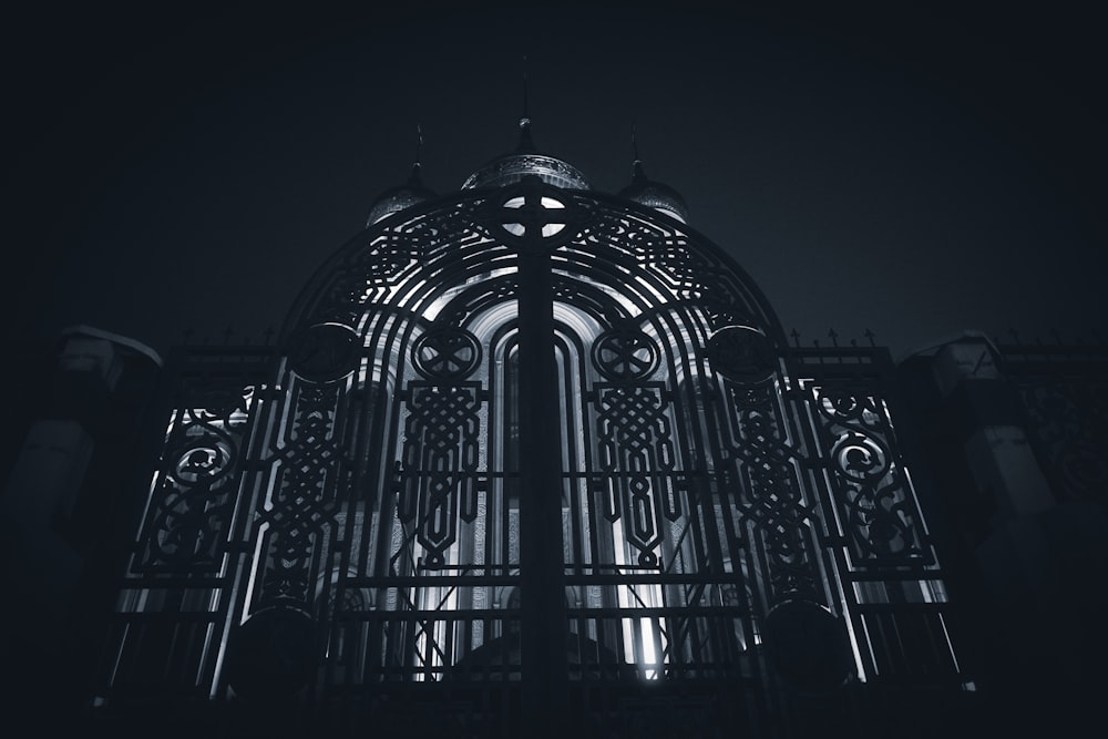 a black and white photo of a gate at night