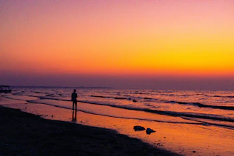 A solitary traveler’s silhouette framed by a golden sunset on a quiet beach