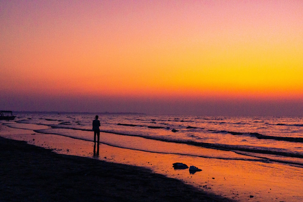 a person standing on a beach at sunset