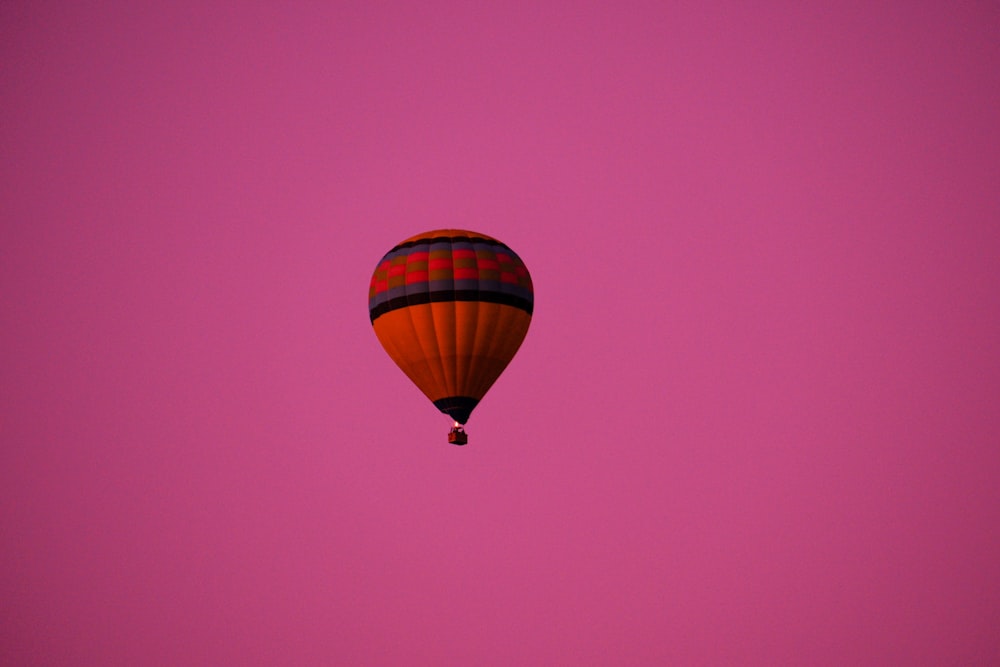 a hot air balloon flying in a pink sky