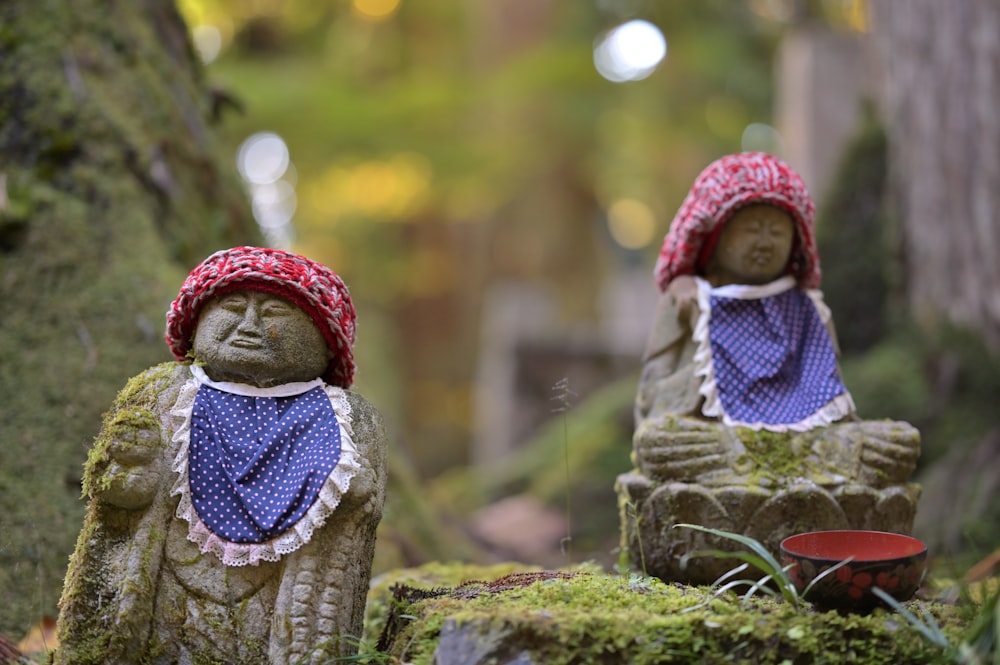 a couple of statues sitting on top of a lush green forest