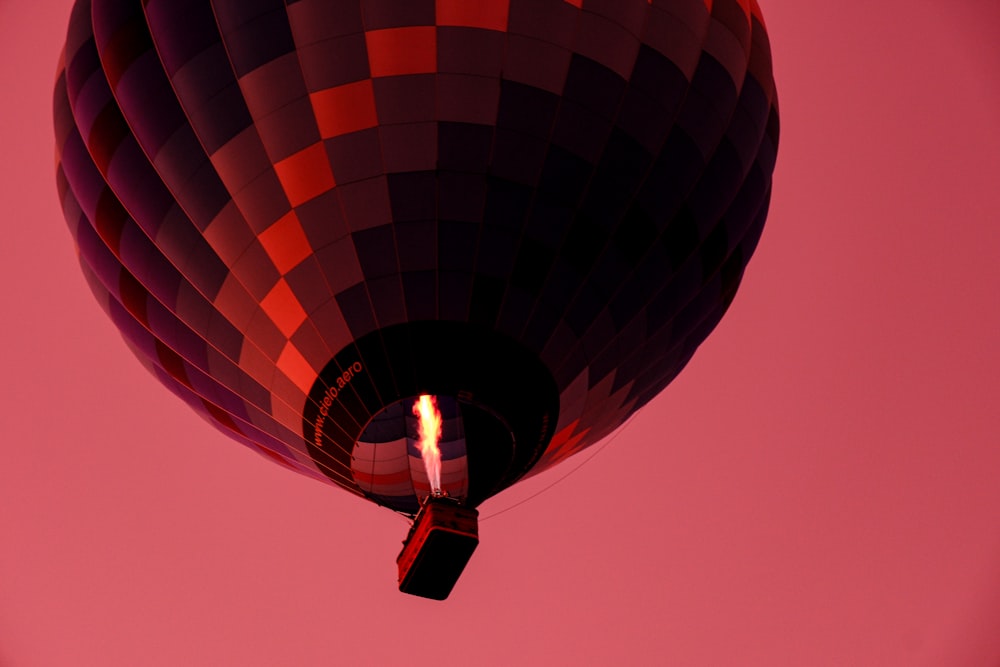 a hot air balloon flying through a pink sky