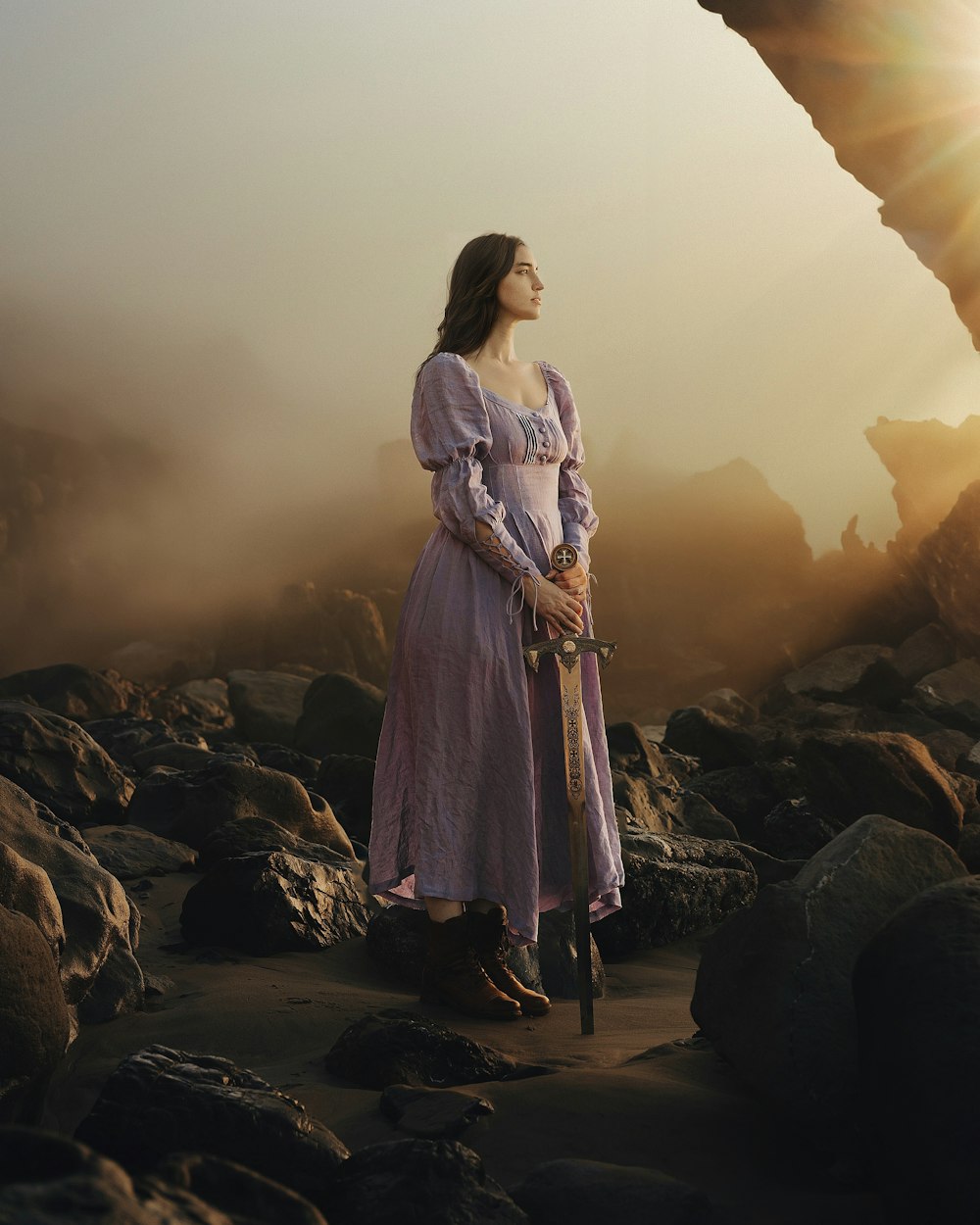 une femme dans une robe violette debout sur des rochers