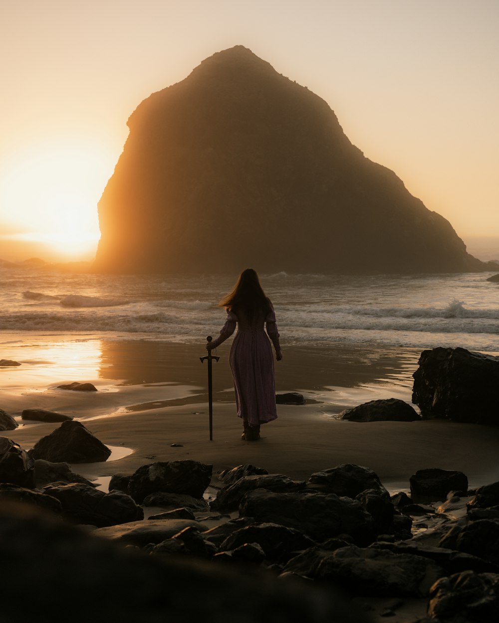 uma mulher em pé em cima de uma praia ao lado do oceano