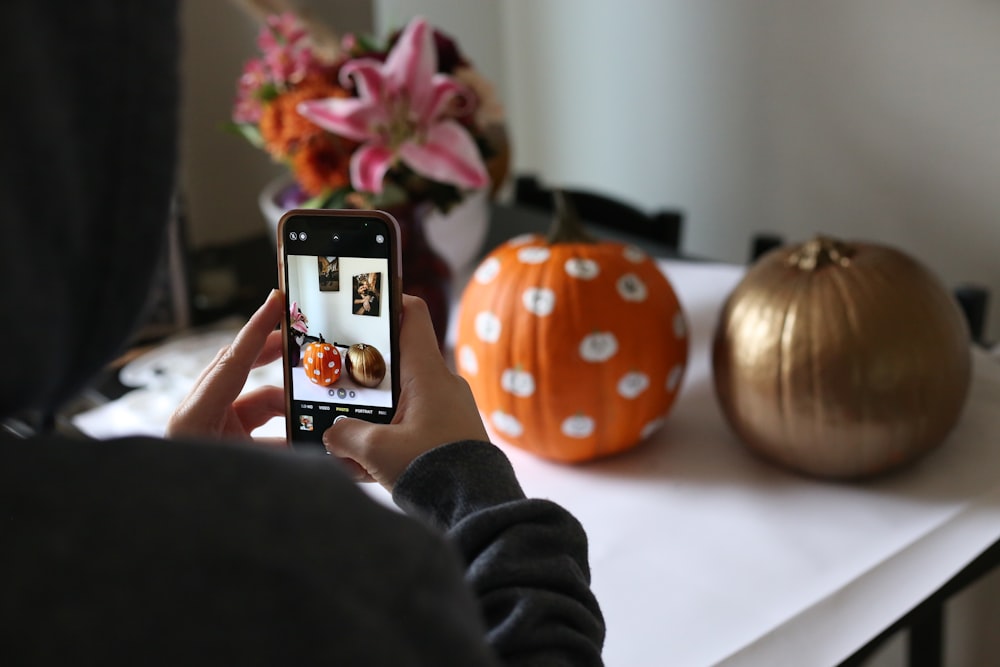a person taking a picture of a pumpkin