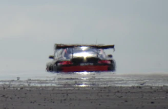 Low-angle view of a performance car’s suspension and wheel well in motion, with blurred asphalt and heat haze.