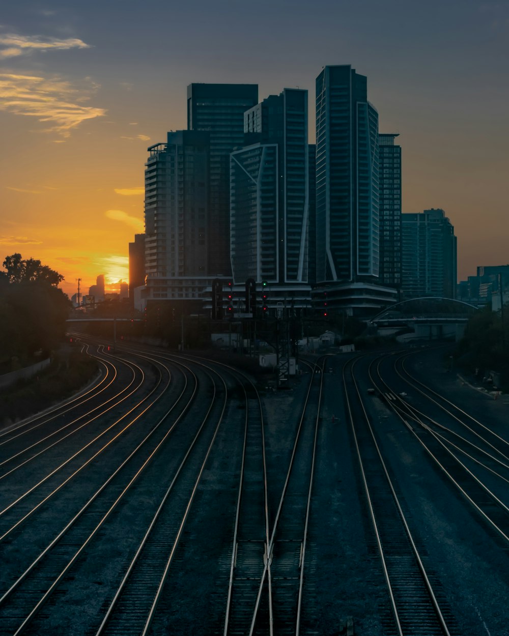 a sunset view of a train track with buildings in the background