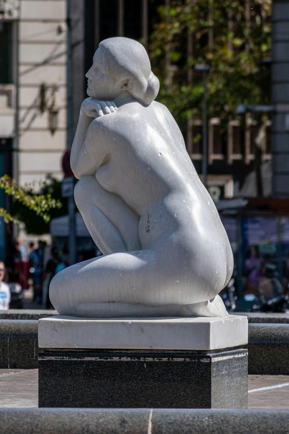 a statue of a seated woman in a city square