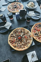 A festive table set with various pizzas and happy guests enjoying the meal