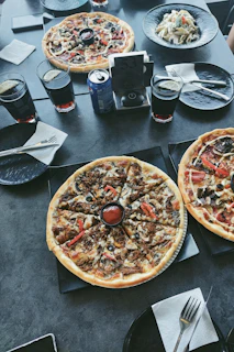A cozy dining table set with different styles of pizza and dipping sauces.
