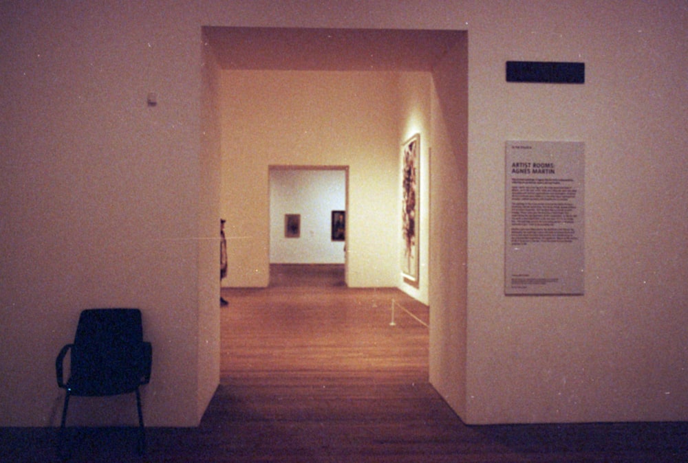 an empty hallway with a chair and paintings on the wall