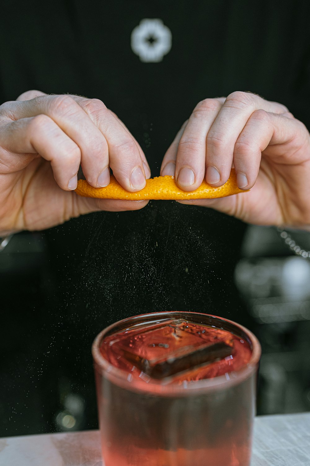 a close up of a person holding an orange near a drink