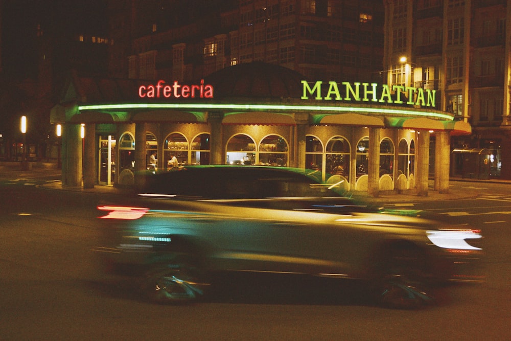 a car driving past a restaurant at night