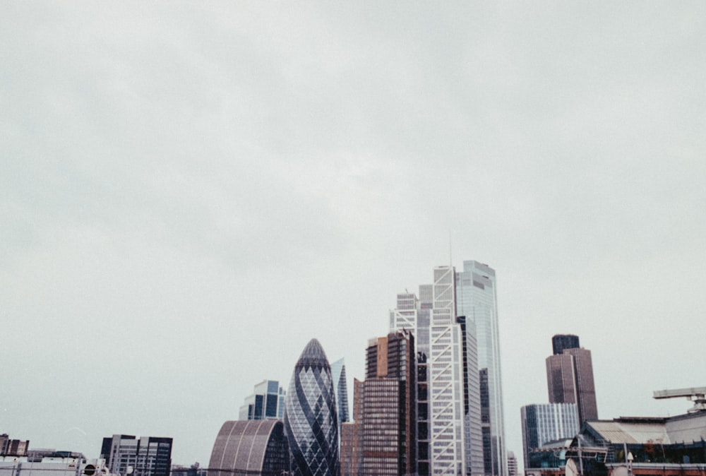 a city skyline with tall buildings and a cloudy sky