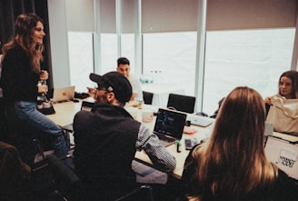 a group of people sitting around a table with laptops