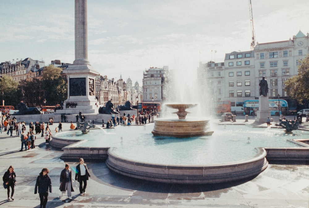 a group of people walking around a fountain