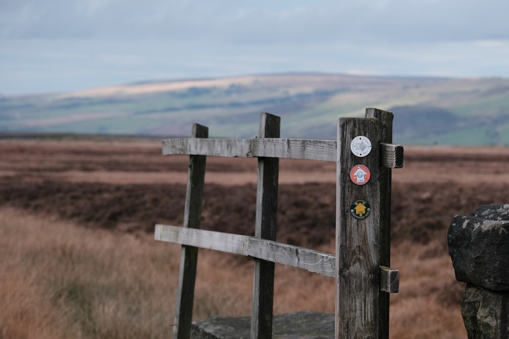 a wooden fence in a field with mountains in the background