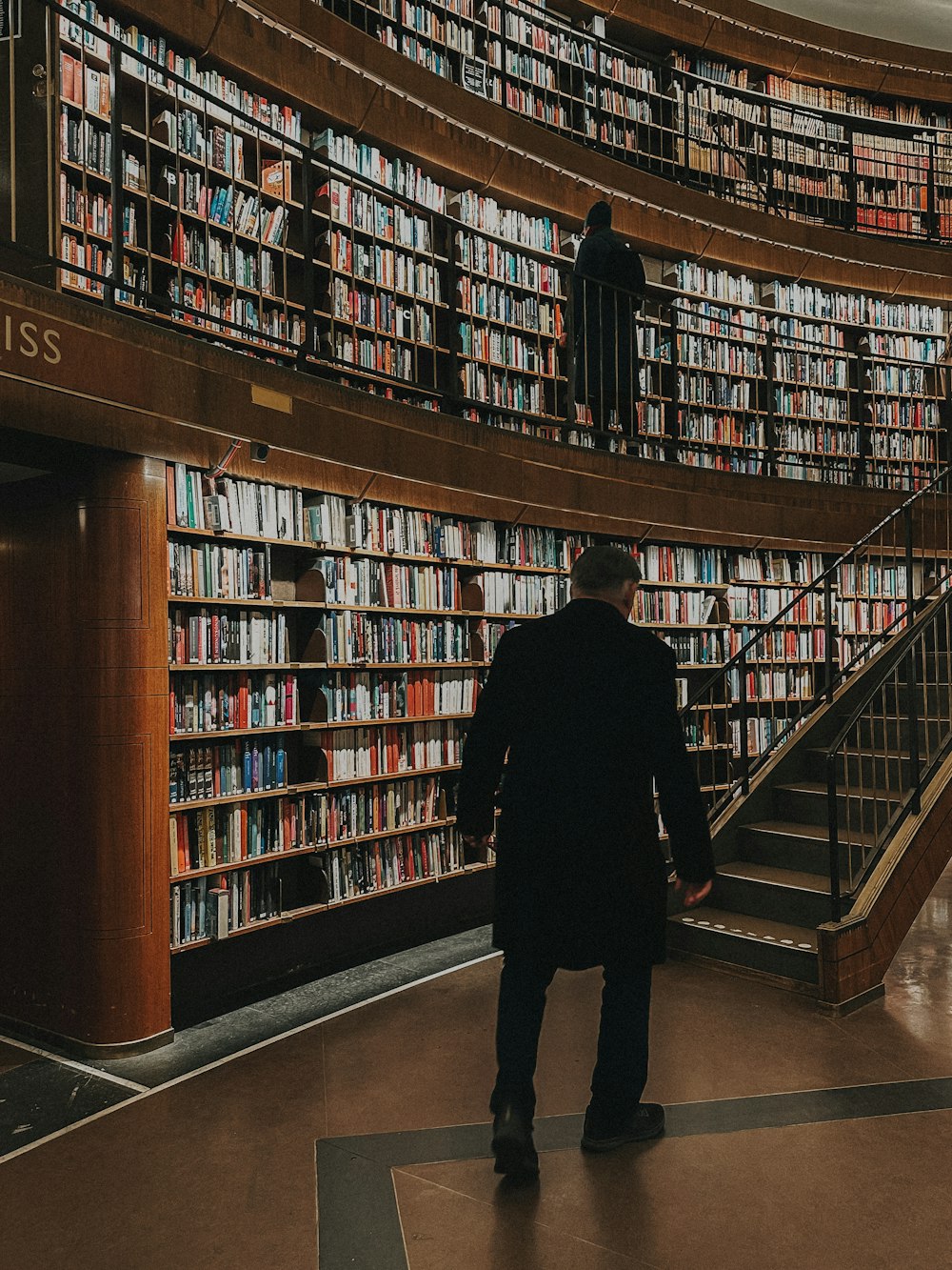 a man standing in front of a library filled with books