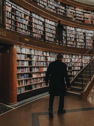 a man standing in front of a library filled with books