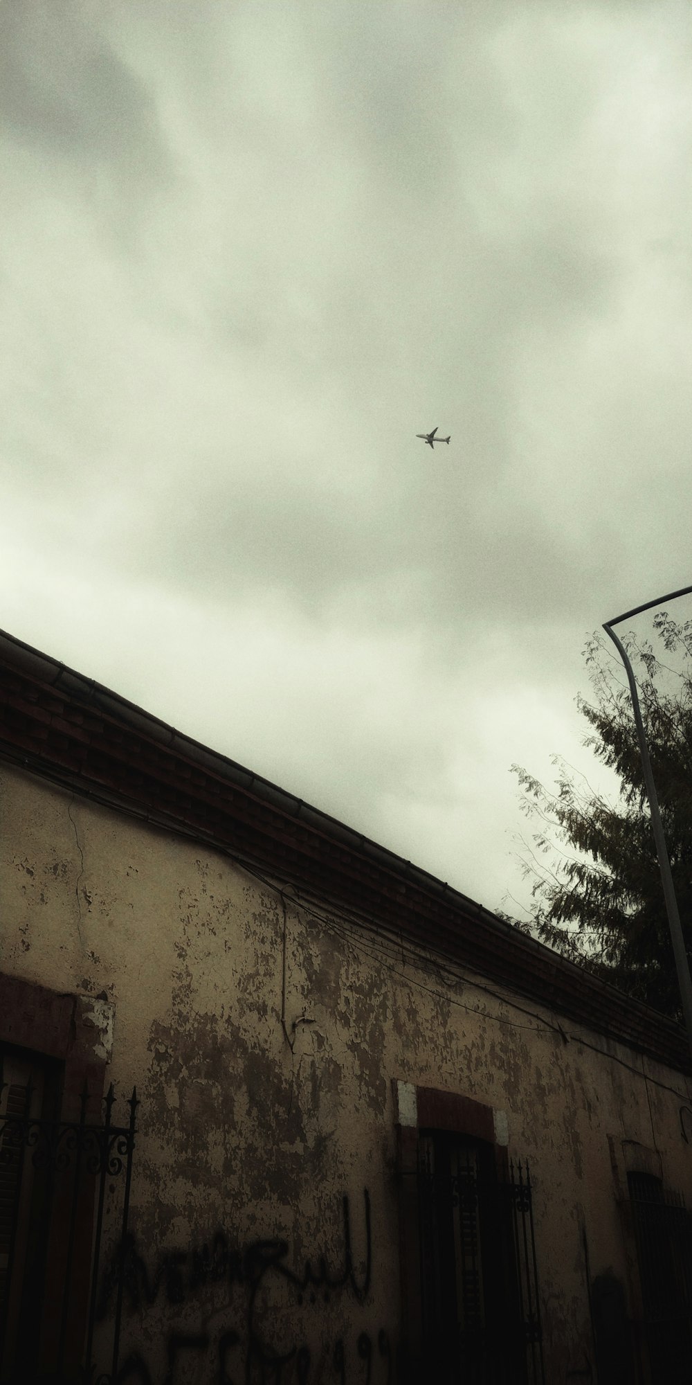 an airplane flying over a building with graffiti on it
