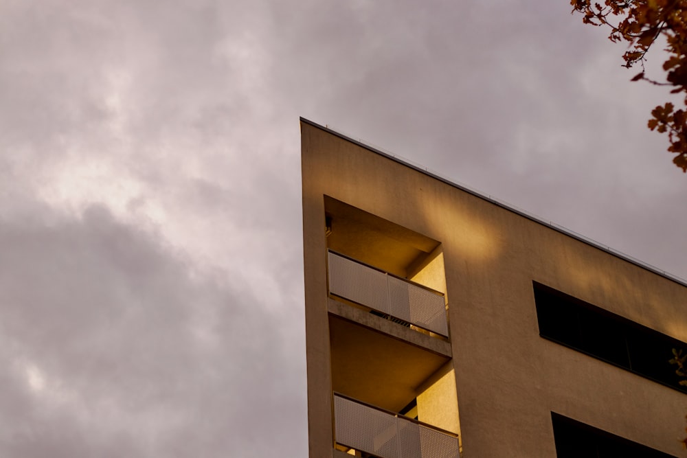 a tall building with balconies against a cloudy sky