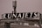 A rooftop structure featuring a large black sign with the word 'LUNAJETS' in bold white letters. The sign is mounted above an industrial-looking building with a complex array of antennas and metal railings.