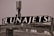 A rooftop structure featuring a large black sign with the word 'LUNAJETS' in bold white letters. The sign is mounted above an industrial-looking building with a complex array of antennas and metal railings.