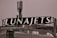 A rooftop structure featuring a large black sign with the word 'LUNAJETS' in bold white letters. The sign is mounted above an industrial-looking building with a complex array of antennas and metal railings.