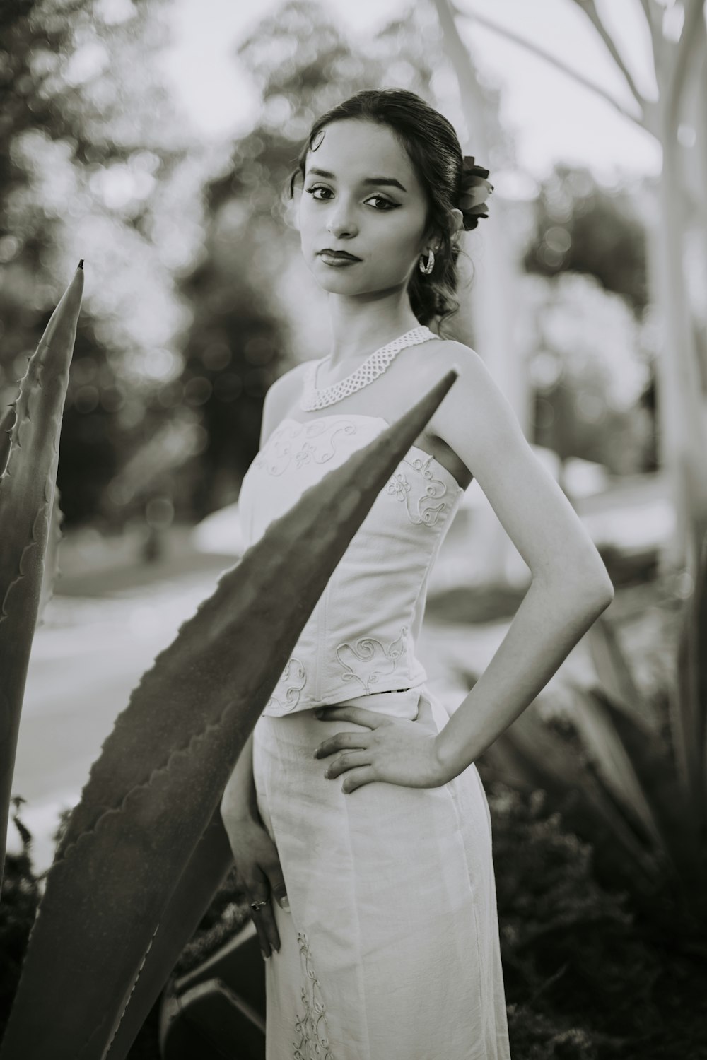 a woman in a white dress standing next to a plant