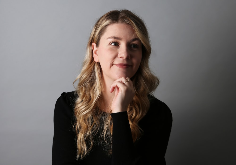 a woman is posing for a picture with her hand on her chin