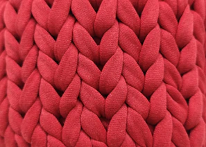 Close-up of a vibrant handmade snood scarf with intricate stitching on a dark background